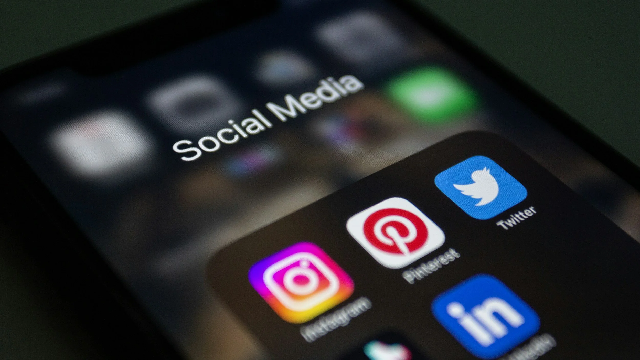 Close-up of a smartphone screen displaying social media app icons including Twitter, Pinterest, and Instagram.