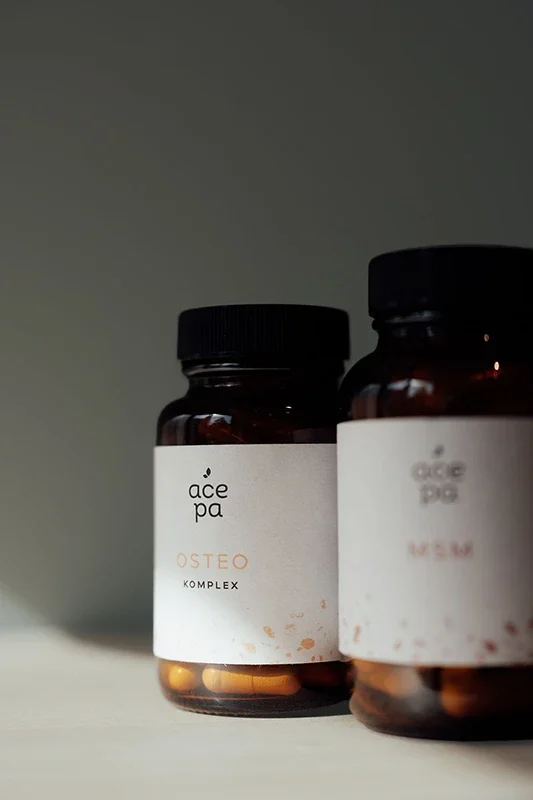 Zwei braune Pillen- oder Supplement-Gläser mit weißen Etiketten, von denen das eine deutlich sichtbar ist. Das Etikett zeigt die Marke acepa und das Produkt OSTEO KOMPLEX.