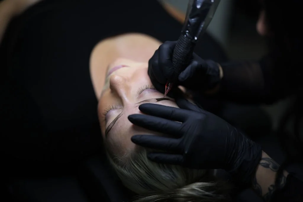 A woman lying down receiving dermaplaning treatment on jaw.