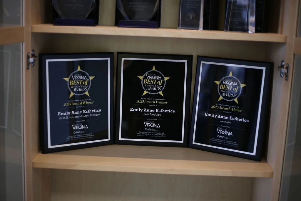 Three award plaques for Emily Anne Esthetics, recognizing her as the 2025 award winner for Best Skin/Dermatology Practice, Best Med Spa, and Best Spa, displayed on a wooden shelf.