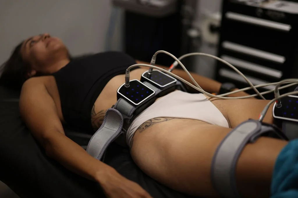 A woman lying down receiving a body contouring treatment.