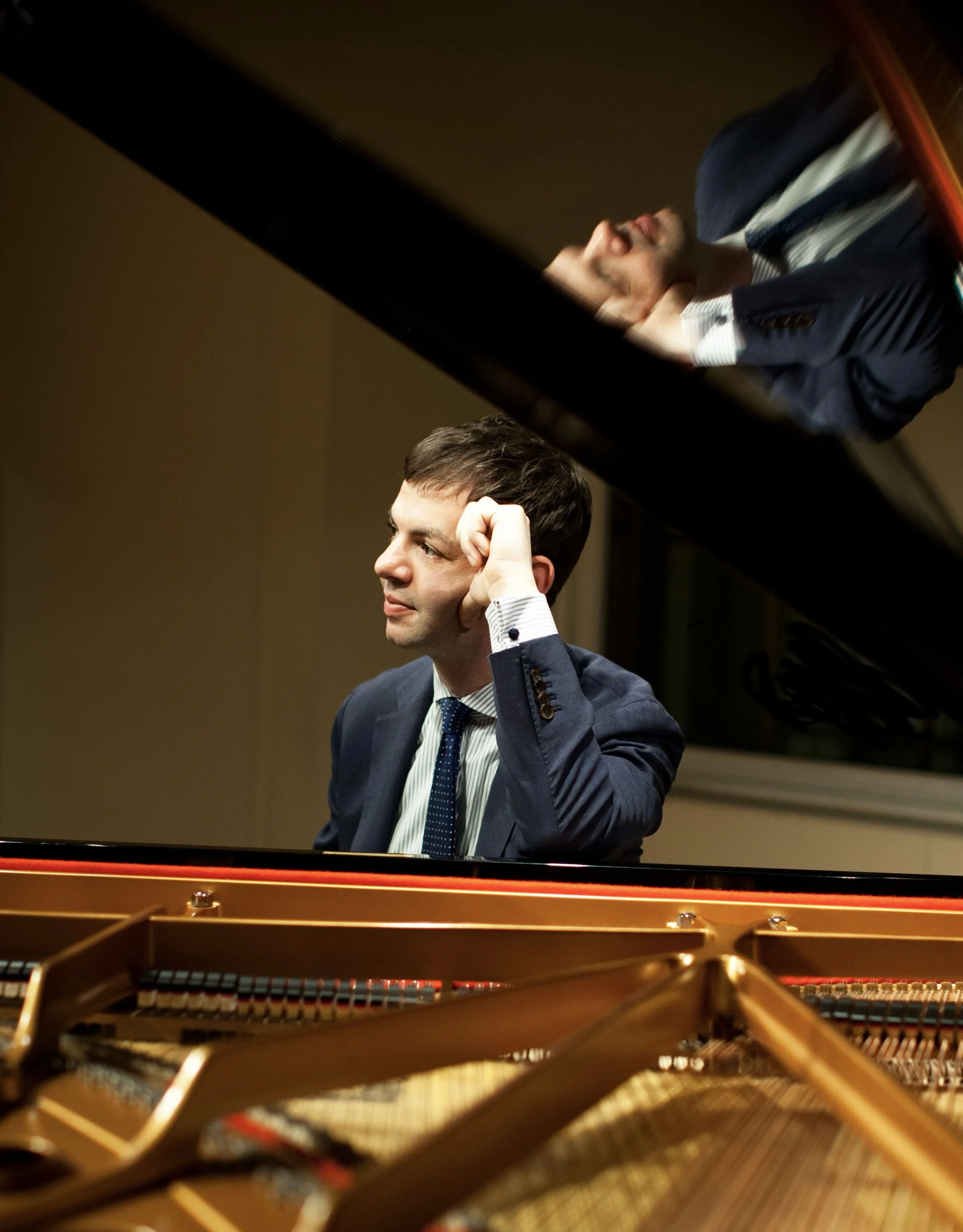 Jazz pianist Dan Nimmer seated at a grand piano wearing a suit.