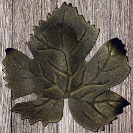 A black, leaf-shaped plate on a wooden surface.