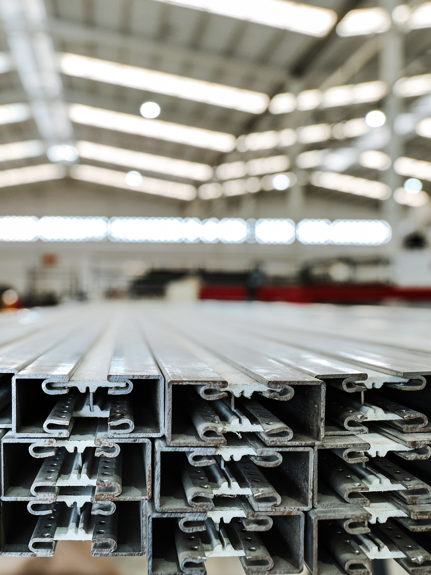 Stacked metal construction beams in an industrial warehouse.