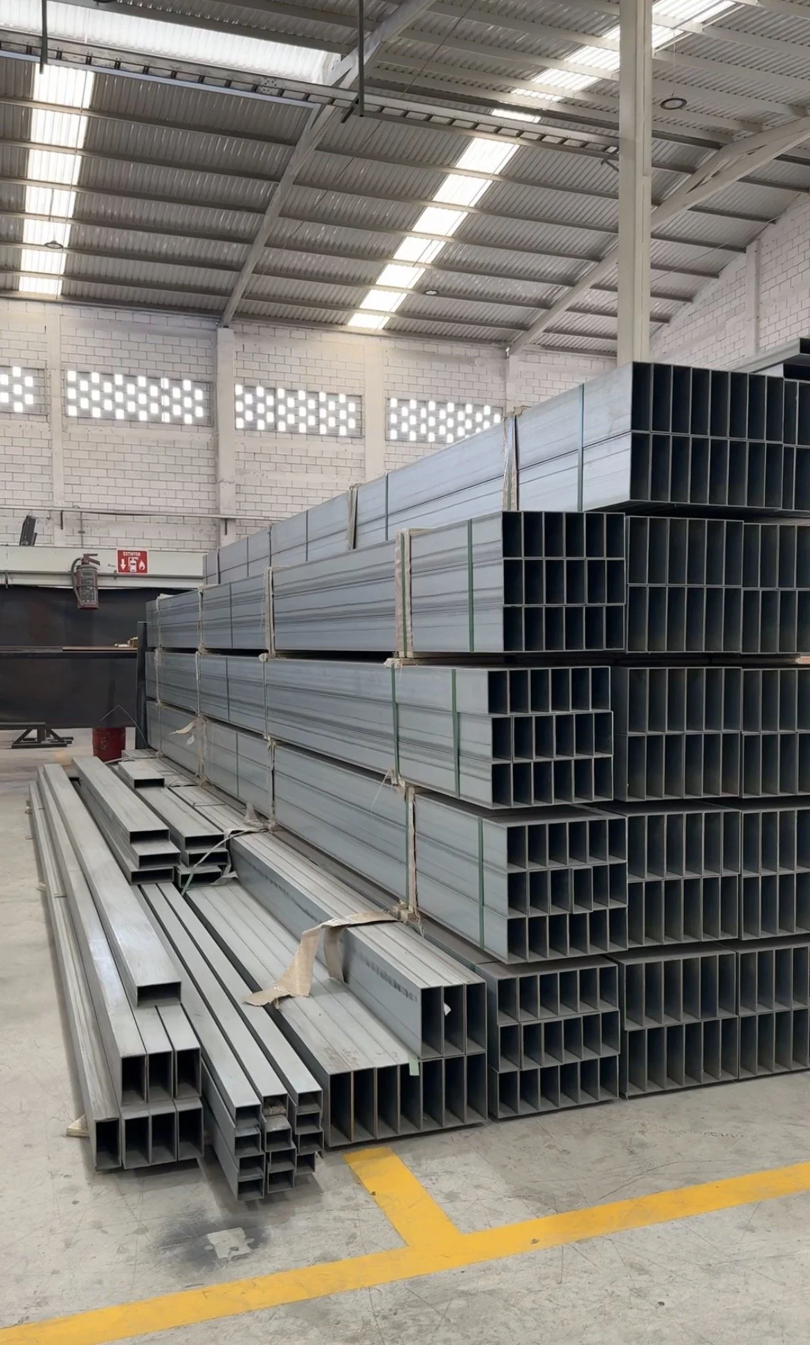 Stacked metal rectangular tubing in a warehouse.