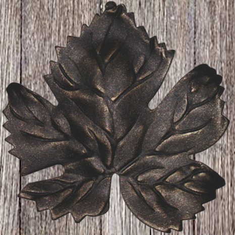 Black, decorative metal leaf-shaped trivet or coaster on wooden surface.