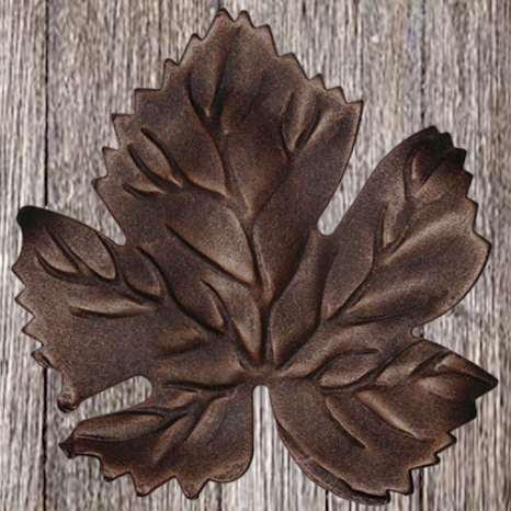 Metal leaf-shaped ornament on wooden background.