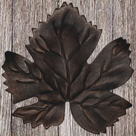 Dark metal leaf-shaped cookie cutter on wooden surface.