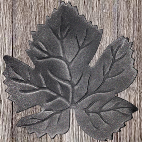 Black, leaf-shaped ornament with vein details on a wooden surface.