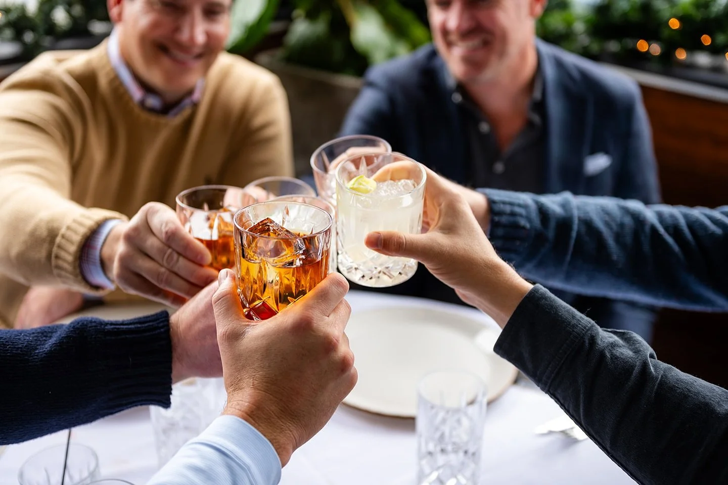 People enjoying drinks together at a table, raising glasses for a toast.