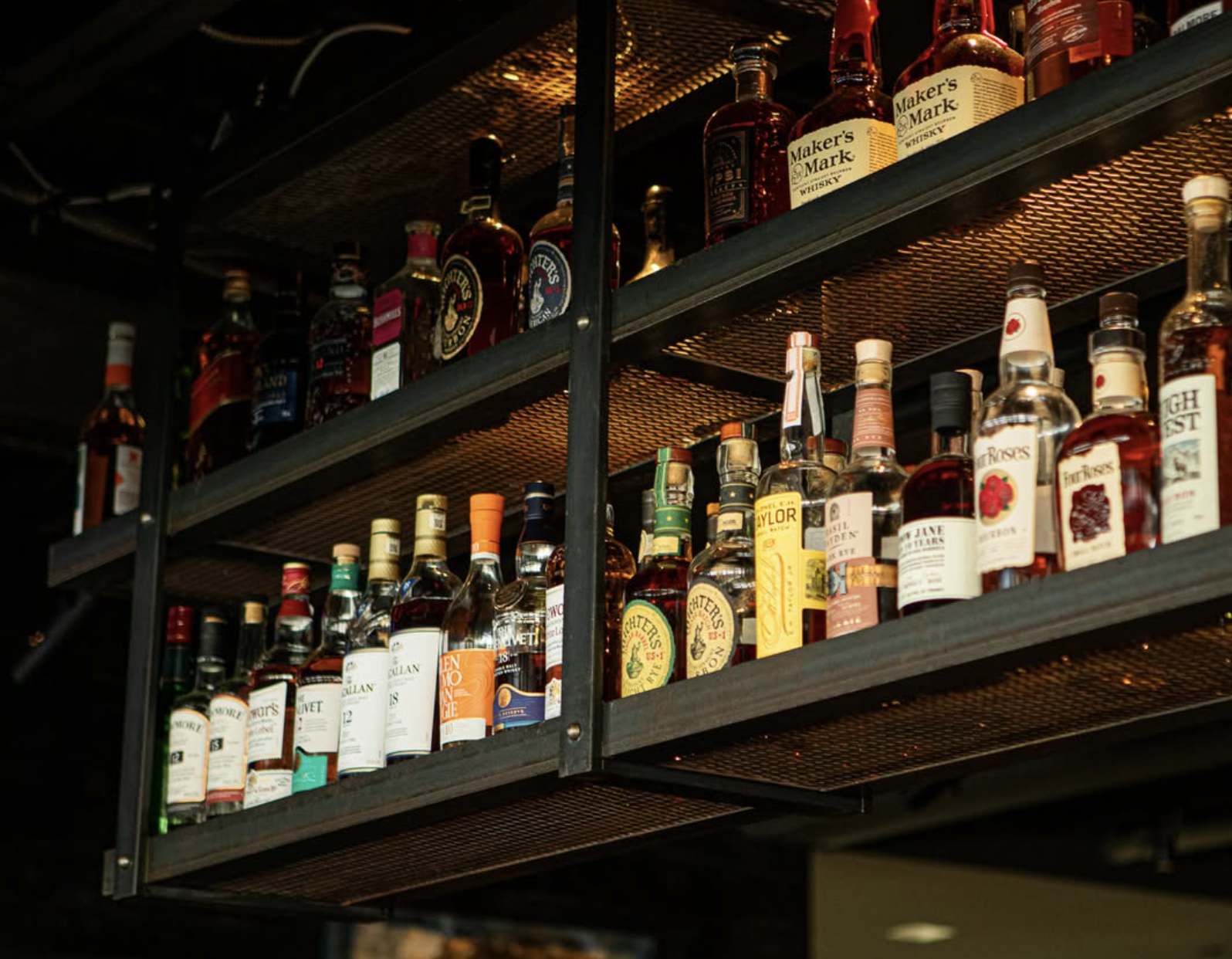 Bar shelf filled with various bottles of whiskey and liquor.
