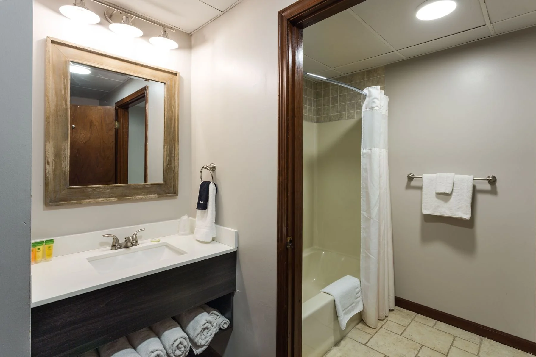 Clean, private full bathroom featuring a tub-shower combo and fresh towels inside a Bear’s Den Lodge hotel room.
