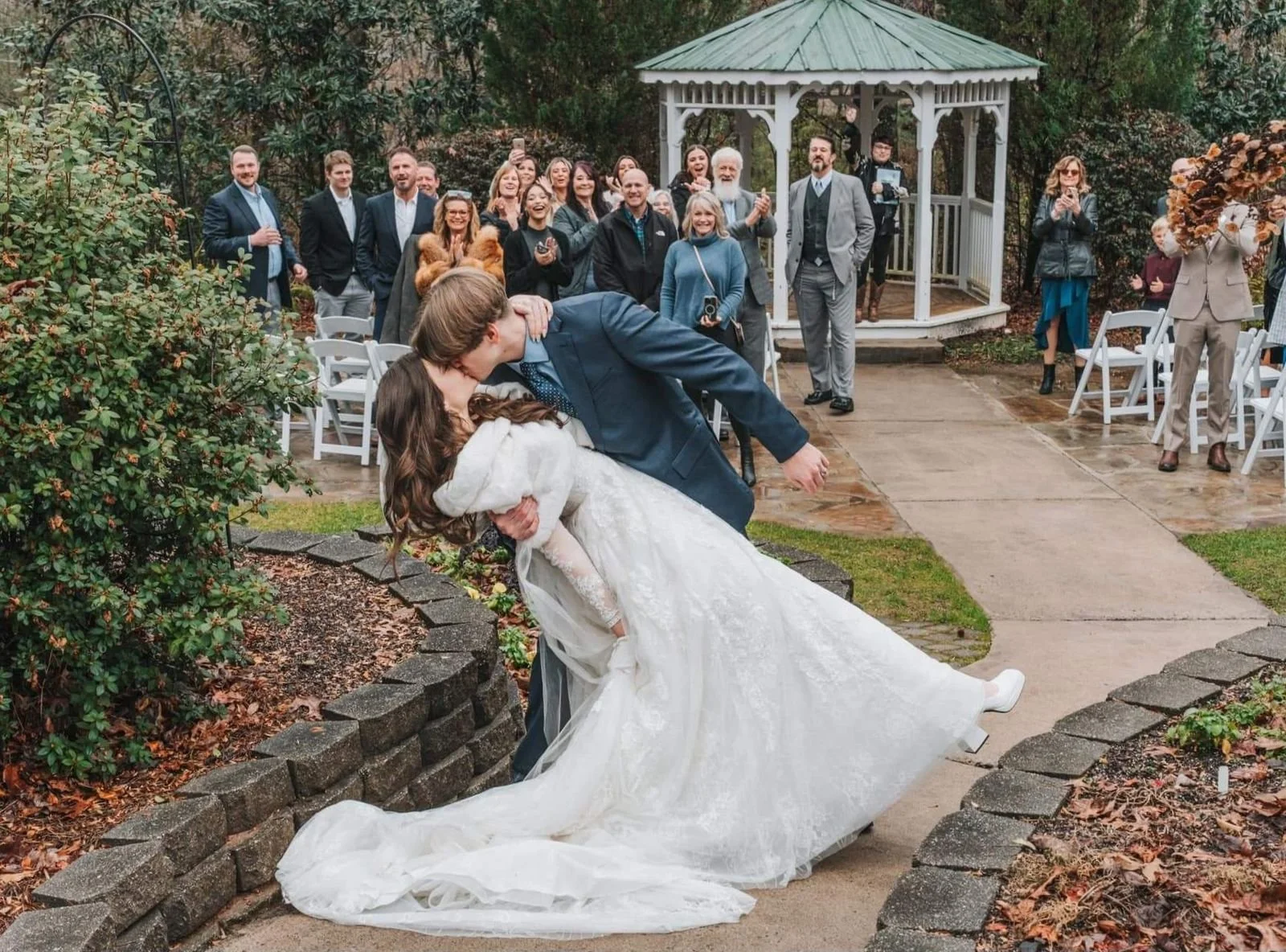 Couple sharing a dance at an outdoor wedding ceremony with guests watching and smiling in the background.
