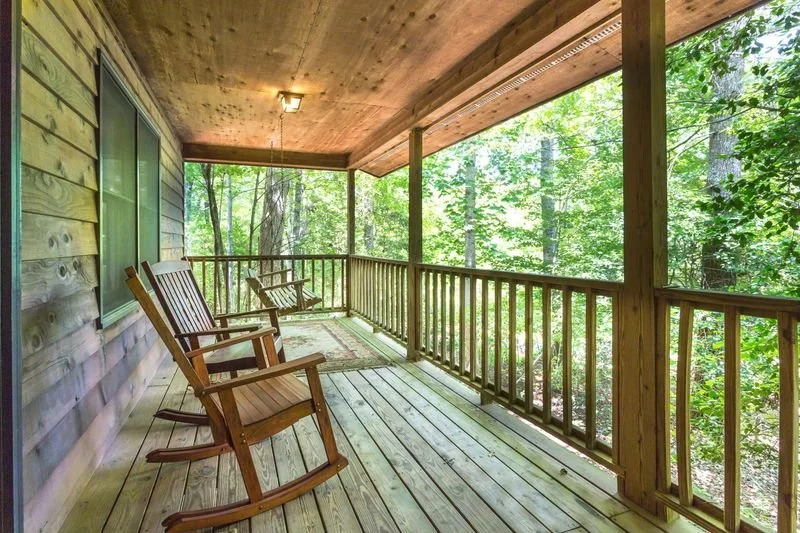 Wooden porch with rocking chairs overlooking a wooded area