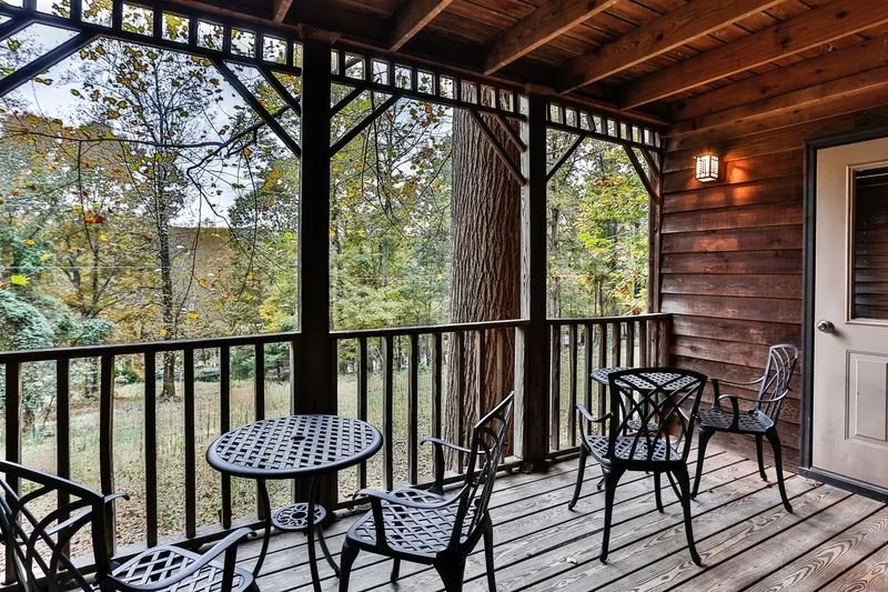 Porch with a black metal table and chairs, shared between 2 rooms.