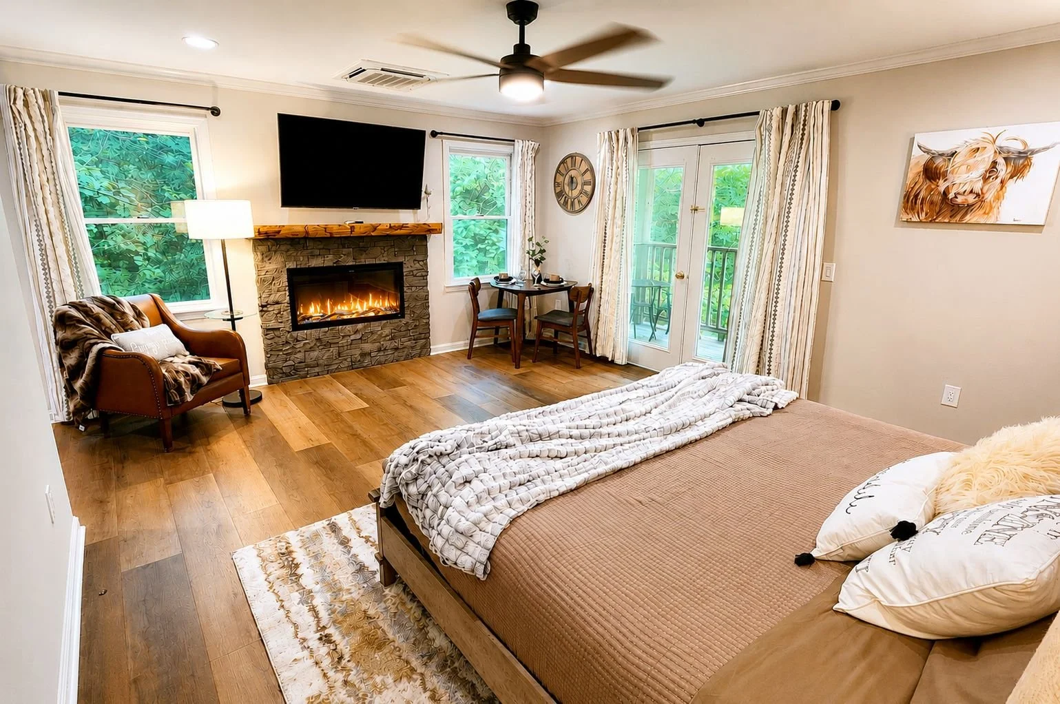 Room with king bed, fireplace, dining table and doors that lead out to a balcony