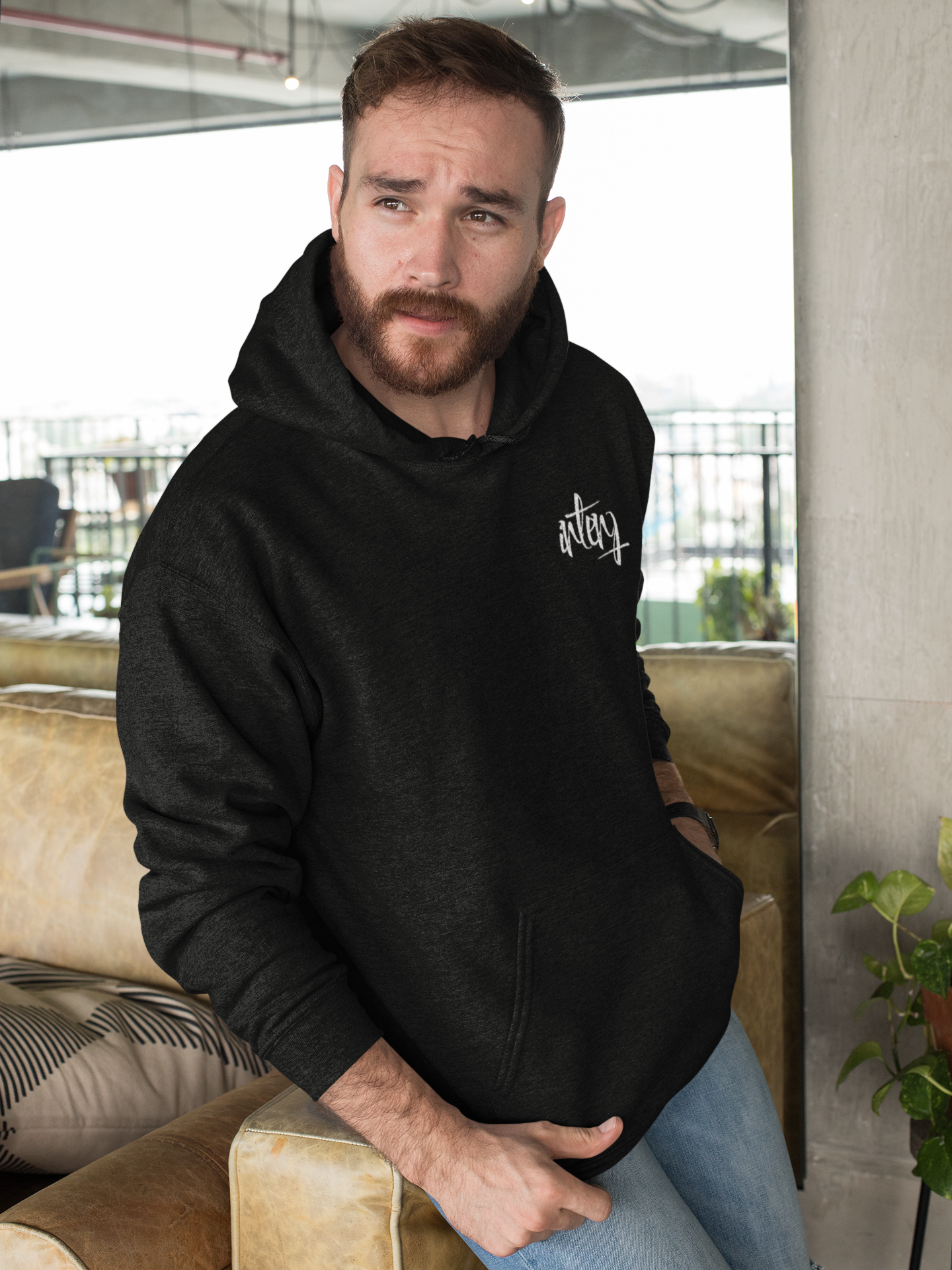 pullover-hoodie-mockup-featuring-a-bearded-man-leaning-over-a-sofa-28741.png