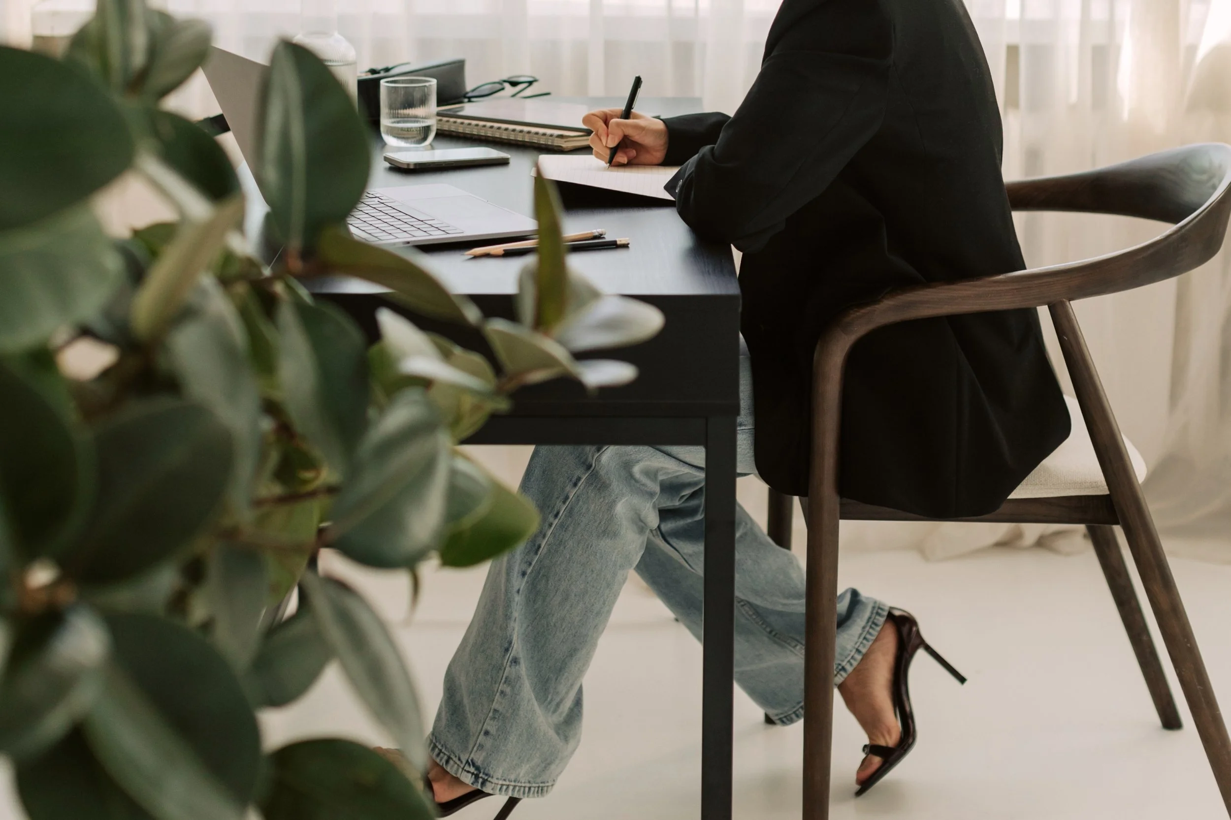 Marketing professional planning strategy at a desk with a laptop and notebook. Person in black business attire Marketing professional in modern business attire representing Cole Creative's professional creative agency approach.