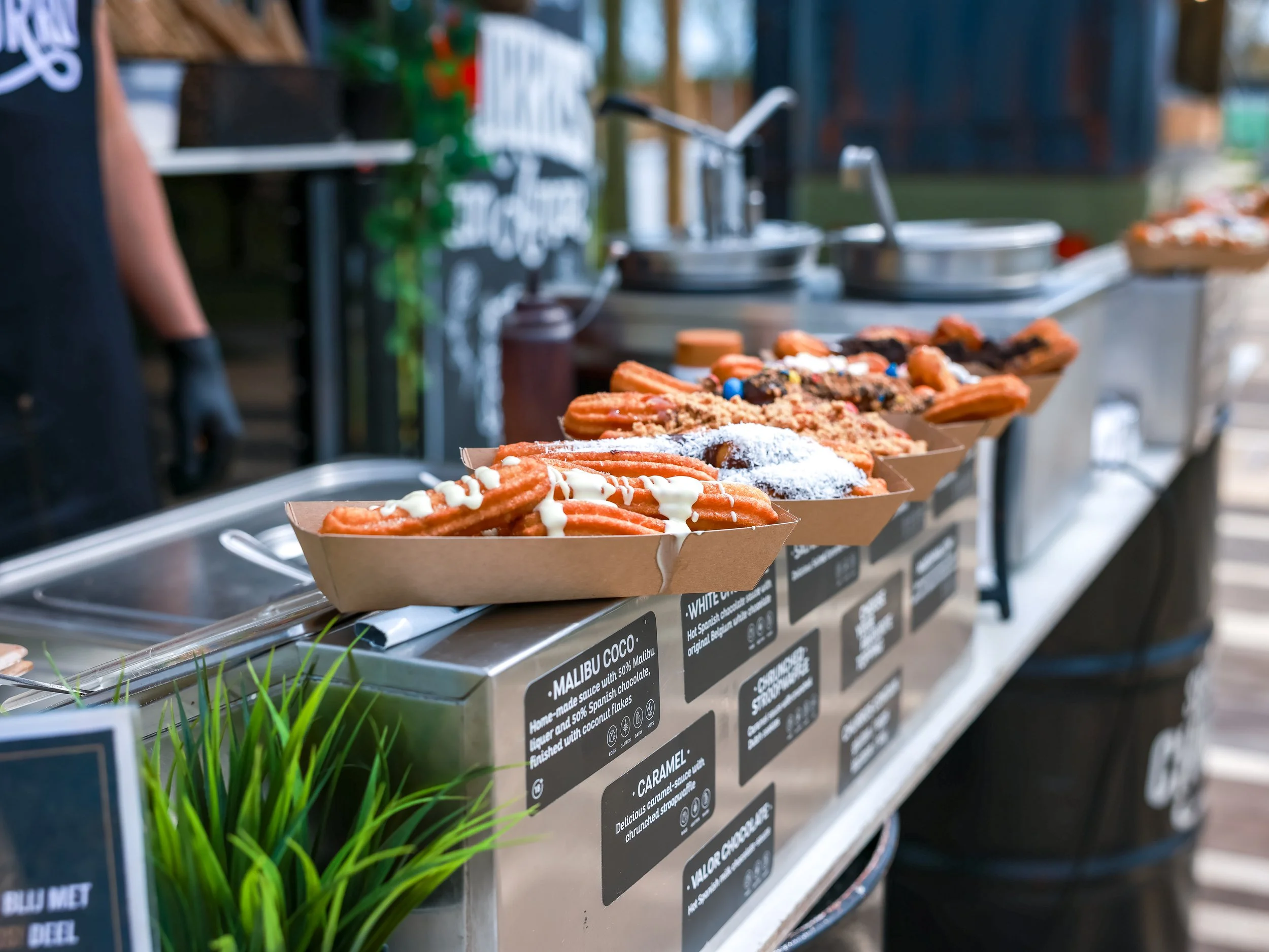 Display of churros with toppings at a food stand.