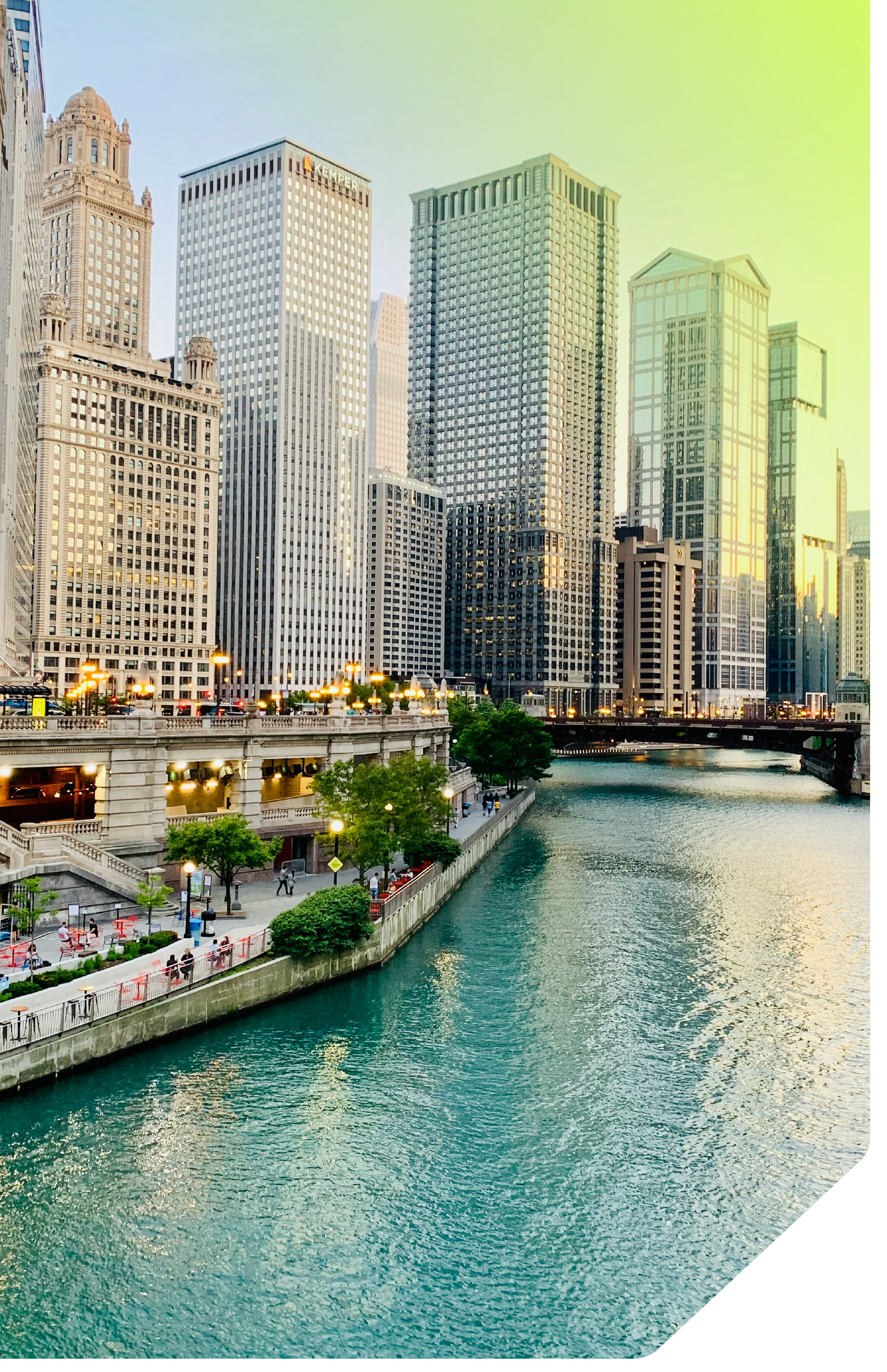 View of a city skyline with tall modern skyscrapers next to a river, and a promenade with pedestrians and trees along the water.