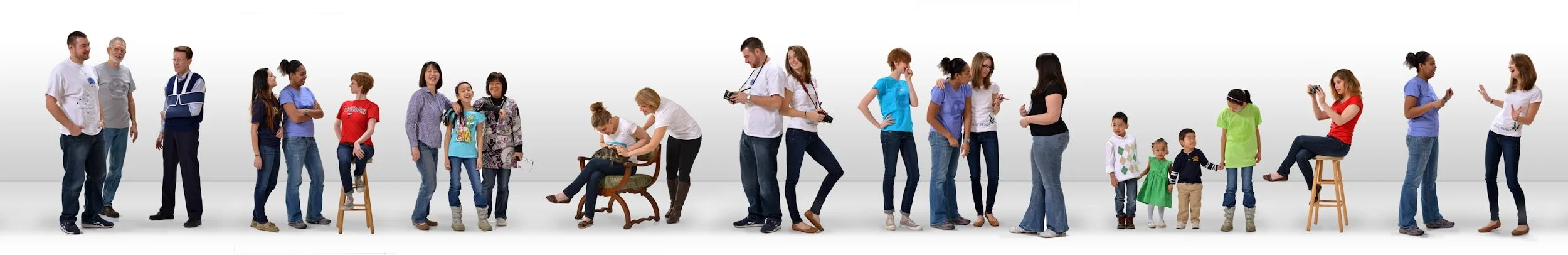 Line of diverse people and children standing and sitting, engaged in conversations and activities, against a plain white background.