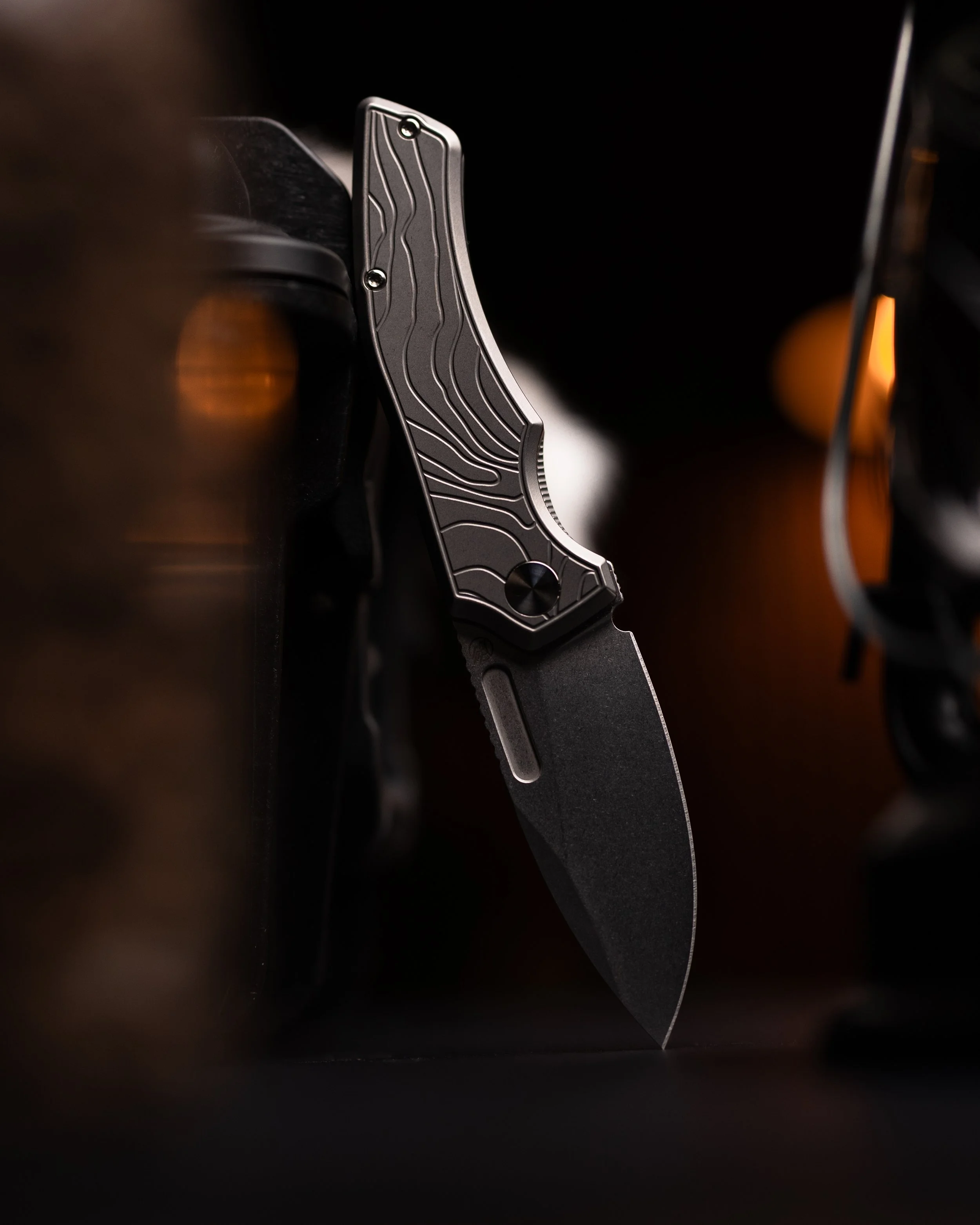 Close-up image of a folding pocket knife with a textured handle, partially open, against a dark background.