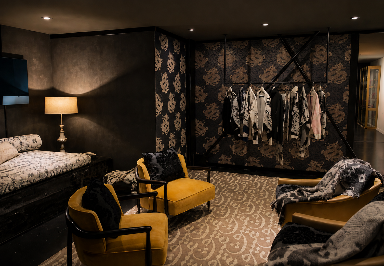Luxurious room with a black and gold aesthetic, featuring two yellow armchairs with black pillows, a patterned sofa with black pillows, a lamp on a side table, and a clothing rack with black and white patterned clothes against a dark wallpapered wall.