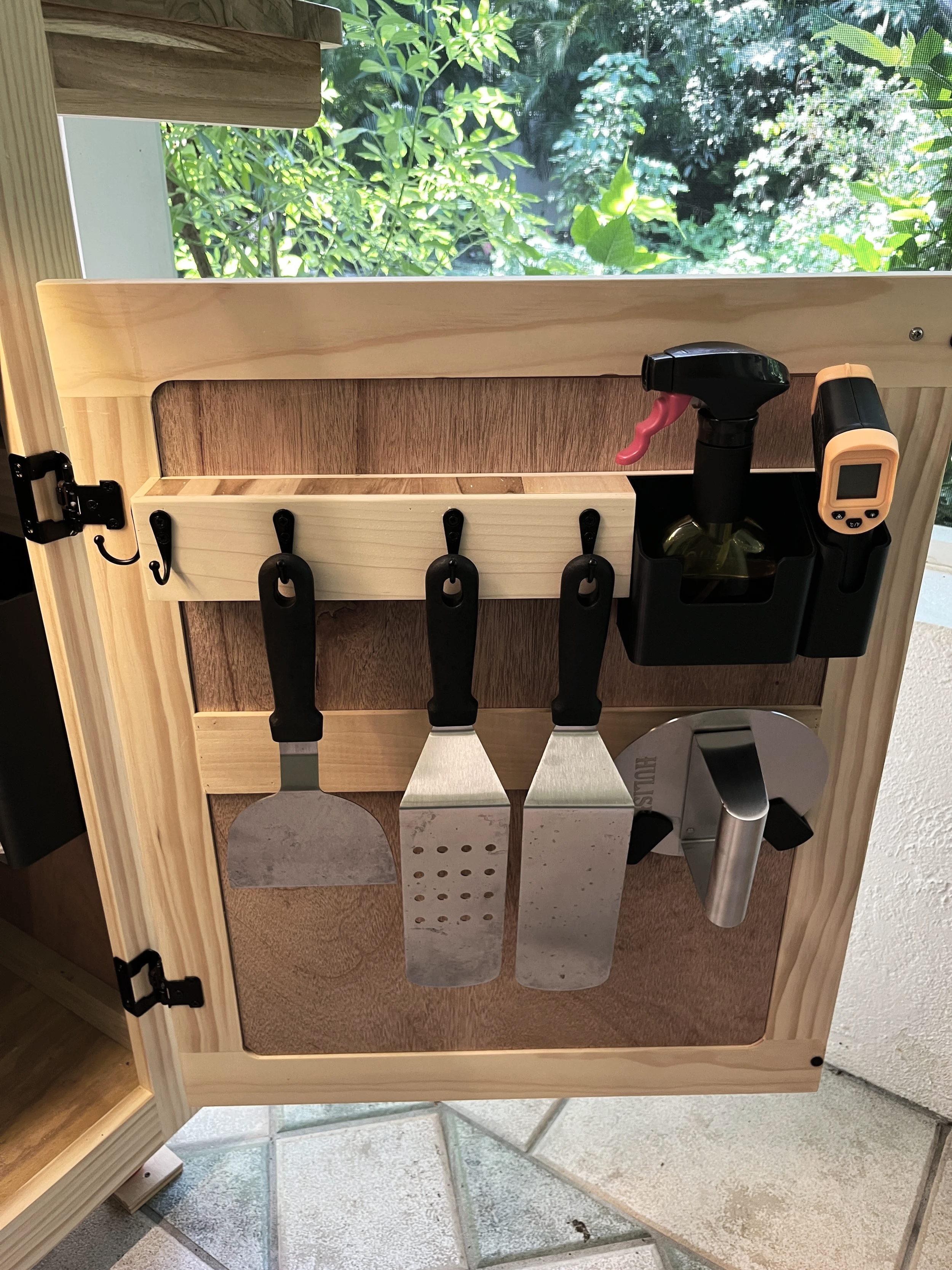 Organized cooking tools stored inside custom outdoor kitchen cabinets