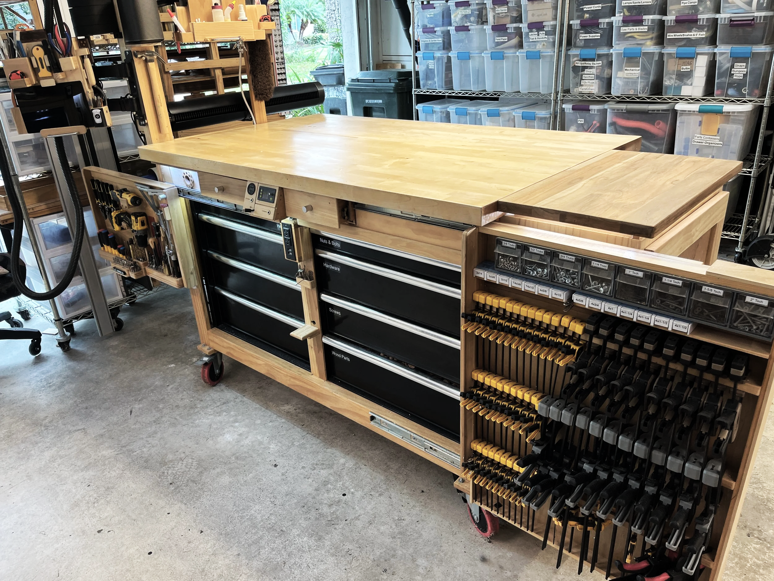Woodworking workbench with expandable wings extended to expose storage drawers
