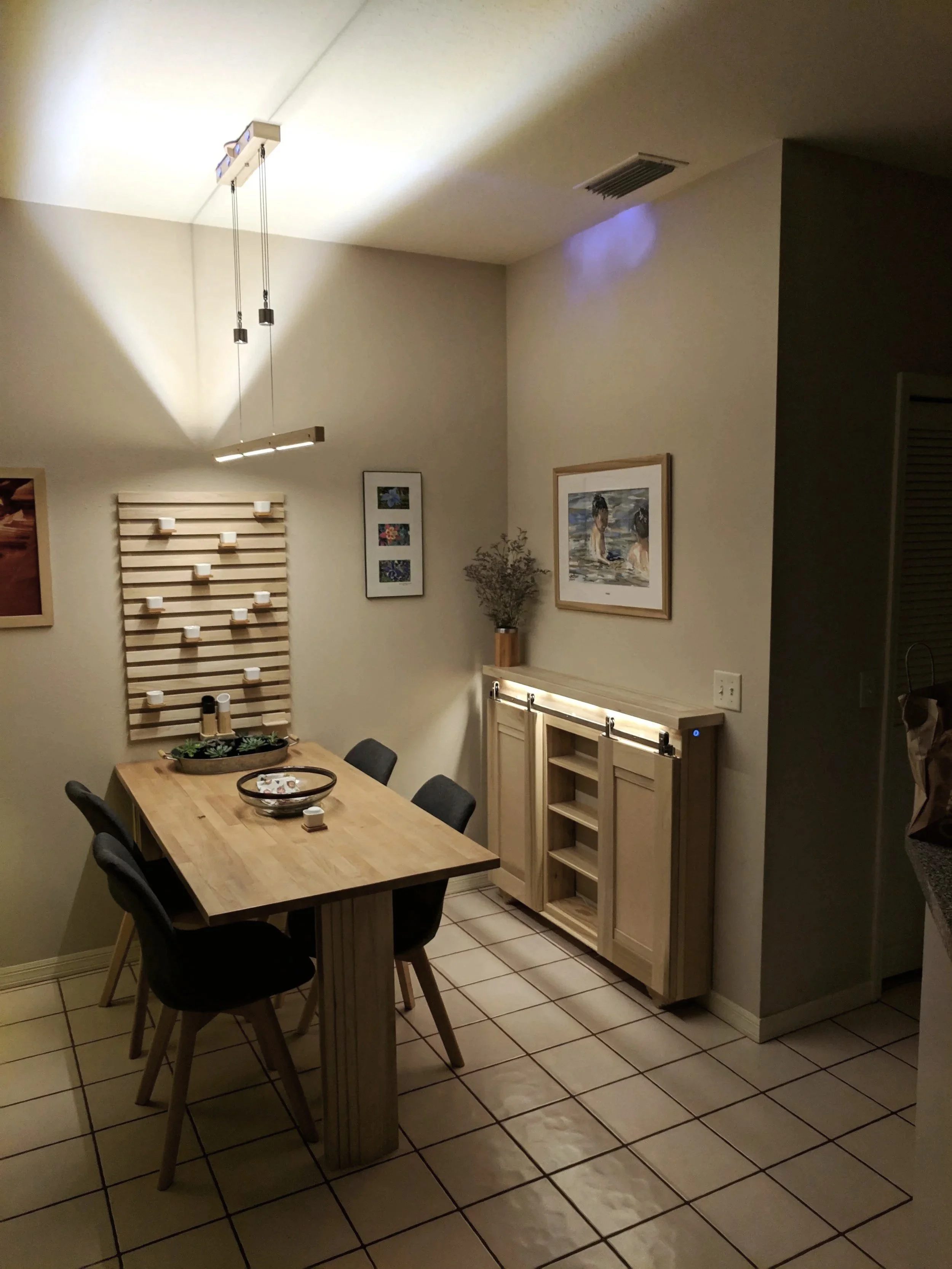 Watercolor display in custom breakfast nook with barn door sideboard and custom built counter weighted hanging light