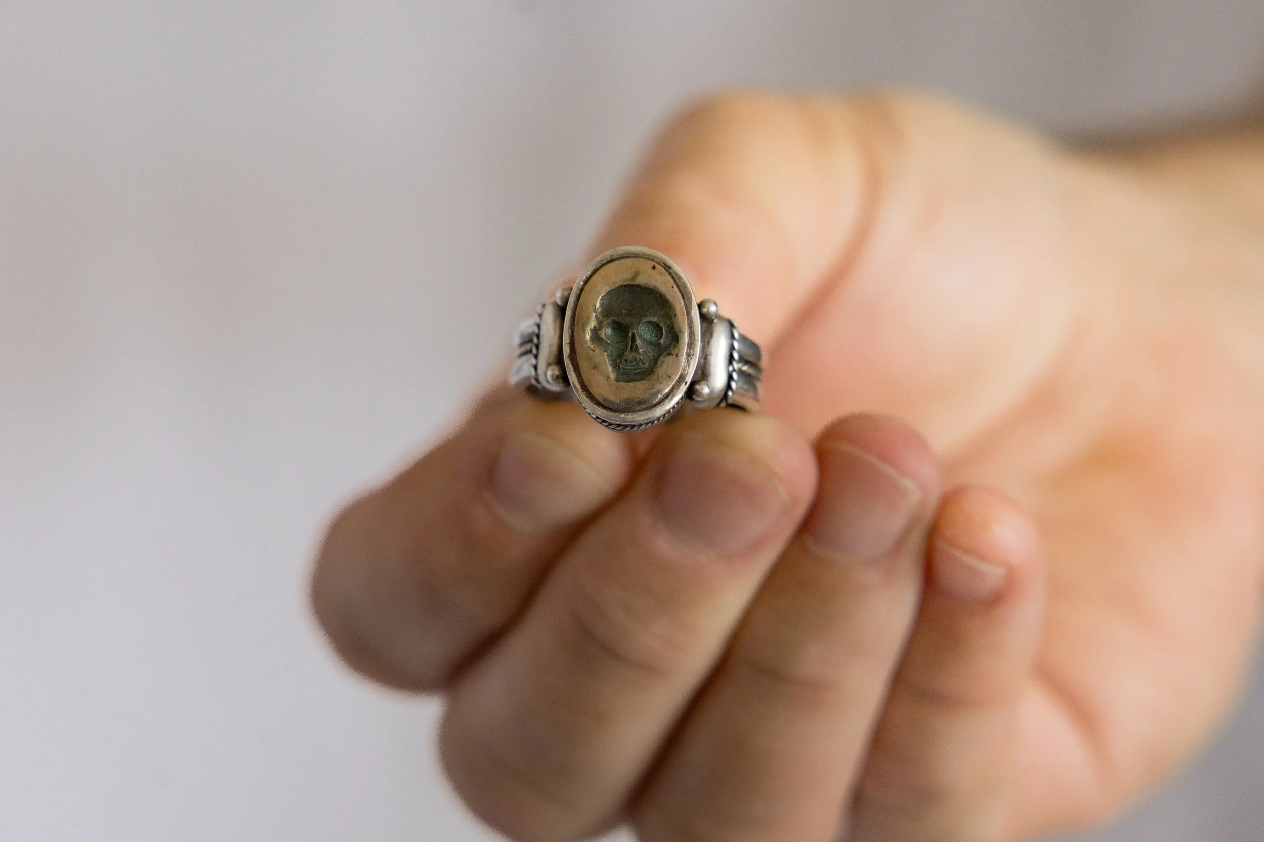 Georgian silver memento mori ring shown  being held on a hand for scale.