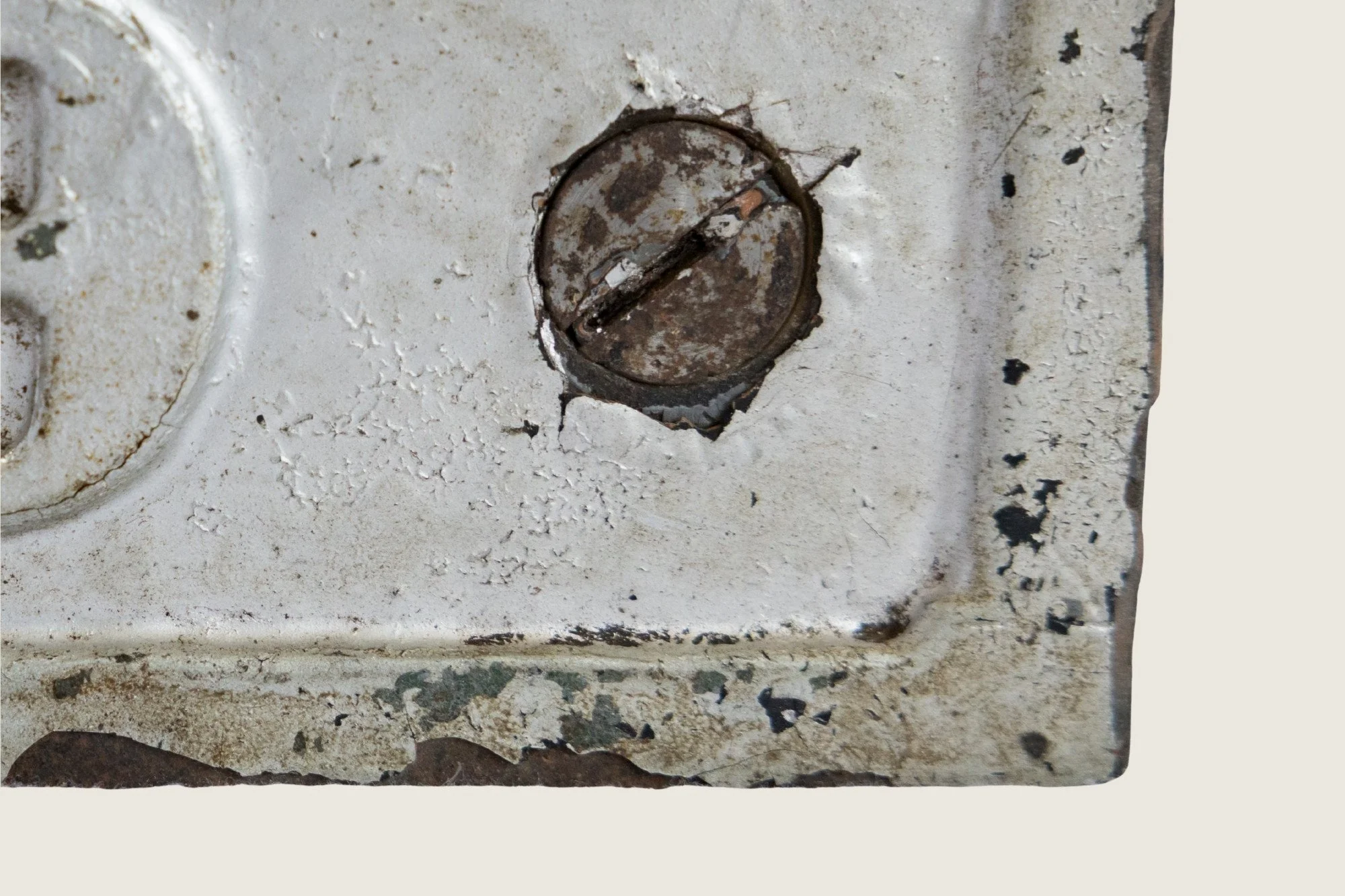 Close detail of a corroded slotted screw set into the painted metal face of the No. 9 identification clamp.