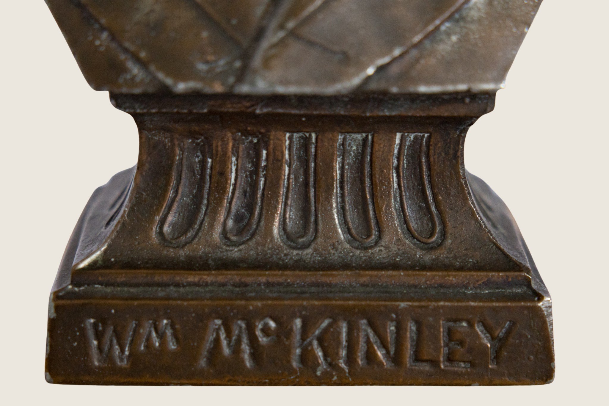 Close detail of the inscribed “Wm McKinley” name on the bust’s pedestal.