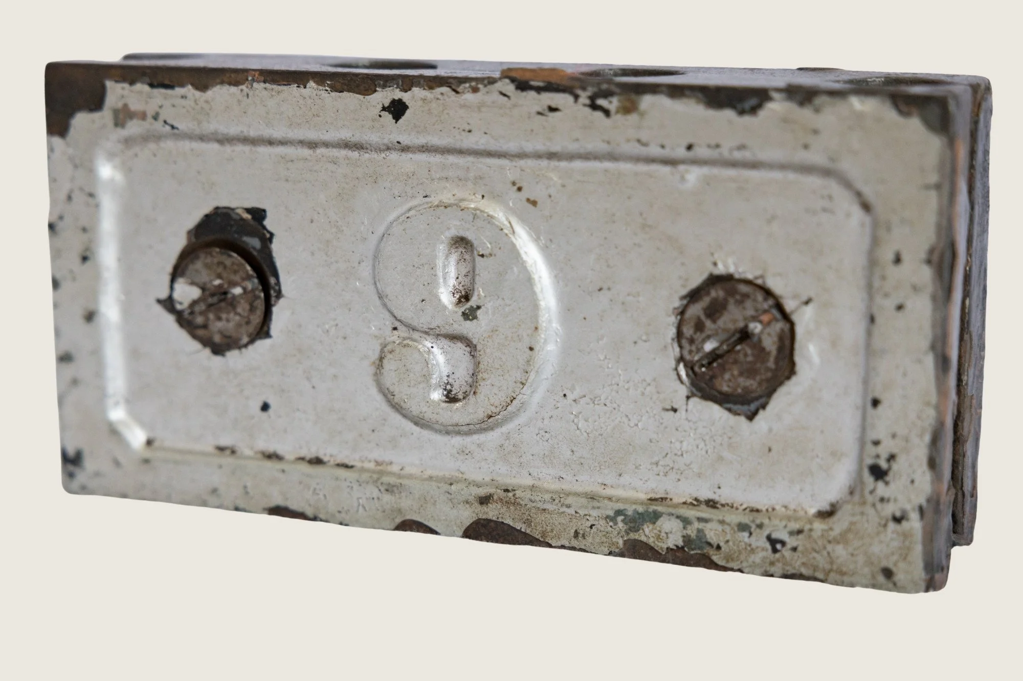 Detail of worn painted metal, rust, scuffs, and surface wear on the No. 9 identification clamp.