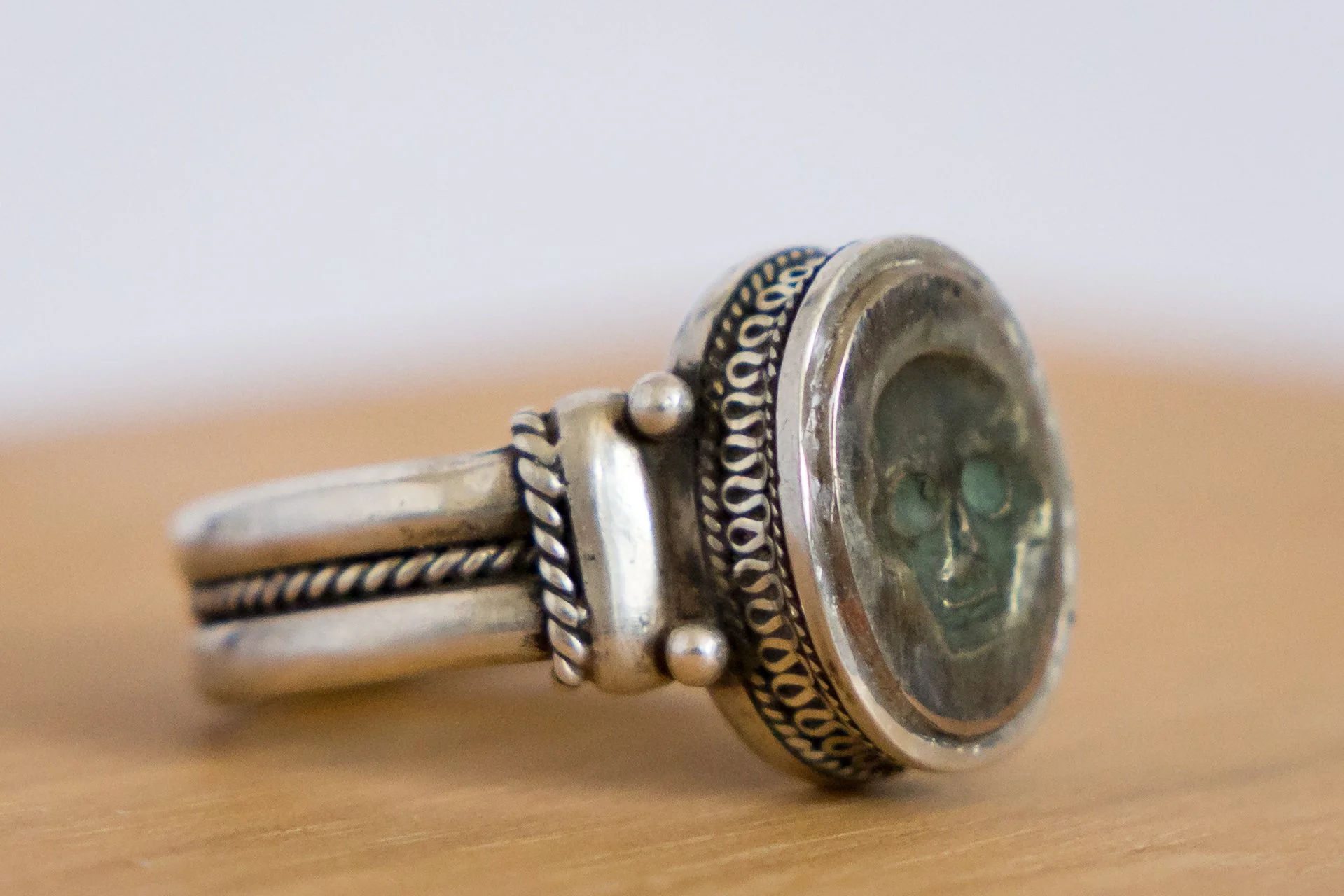 Three-quarter view of the Georgian silver memento mori ring showing the skull bezel and decorative shoulders.