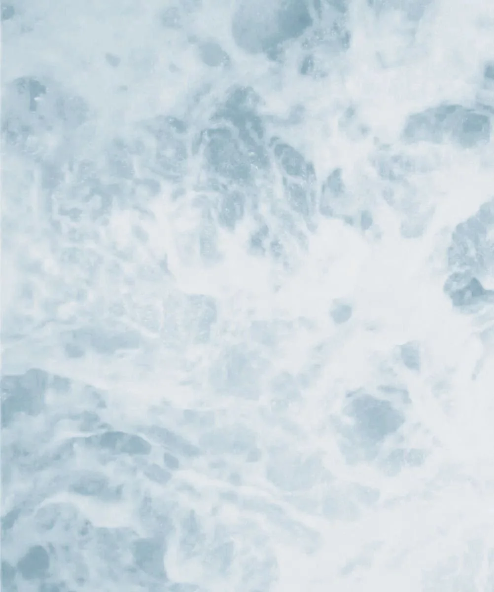 A close-up view of foamy, turbulent water, possibly from the ocean or a river.