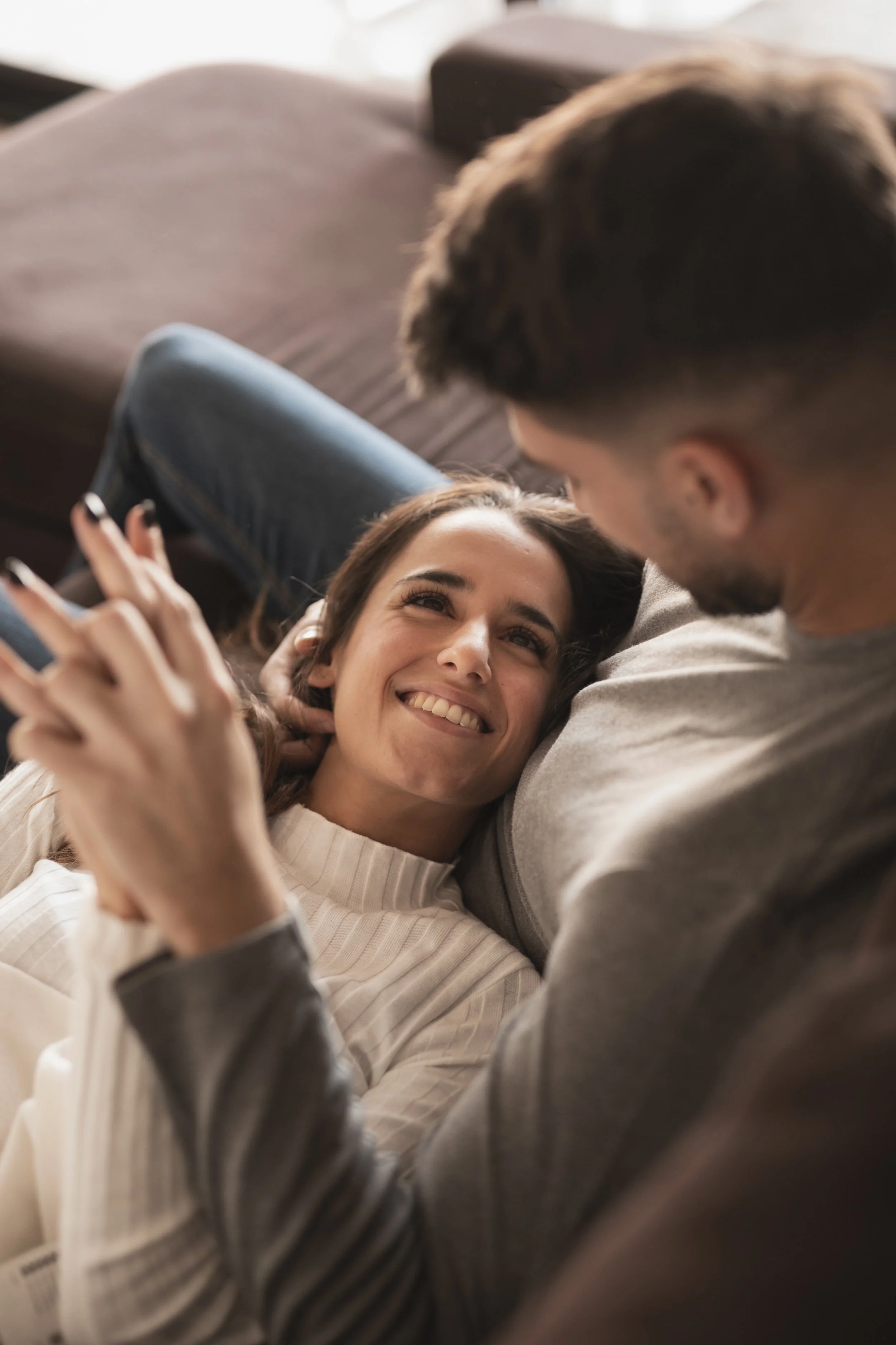 Happy couple on couch, one partner has her head on the lap of the other
