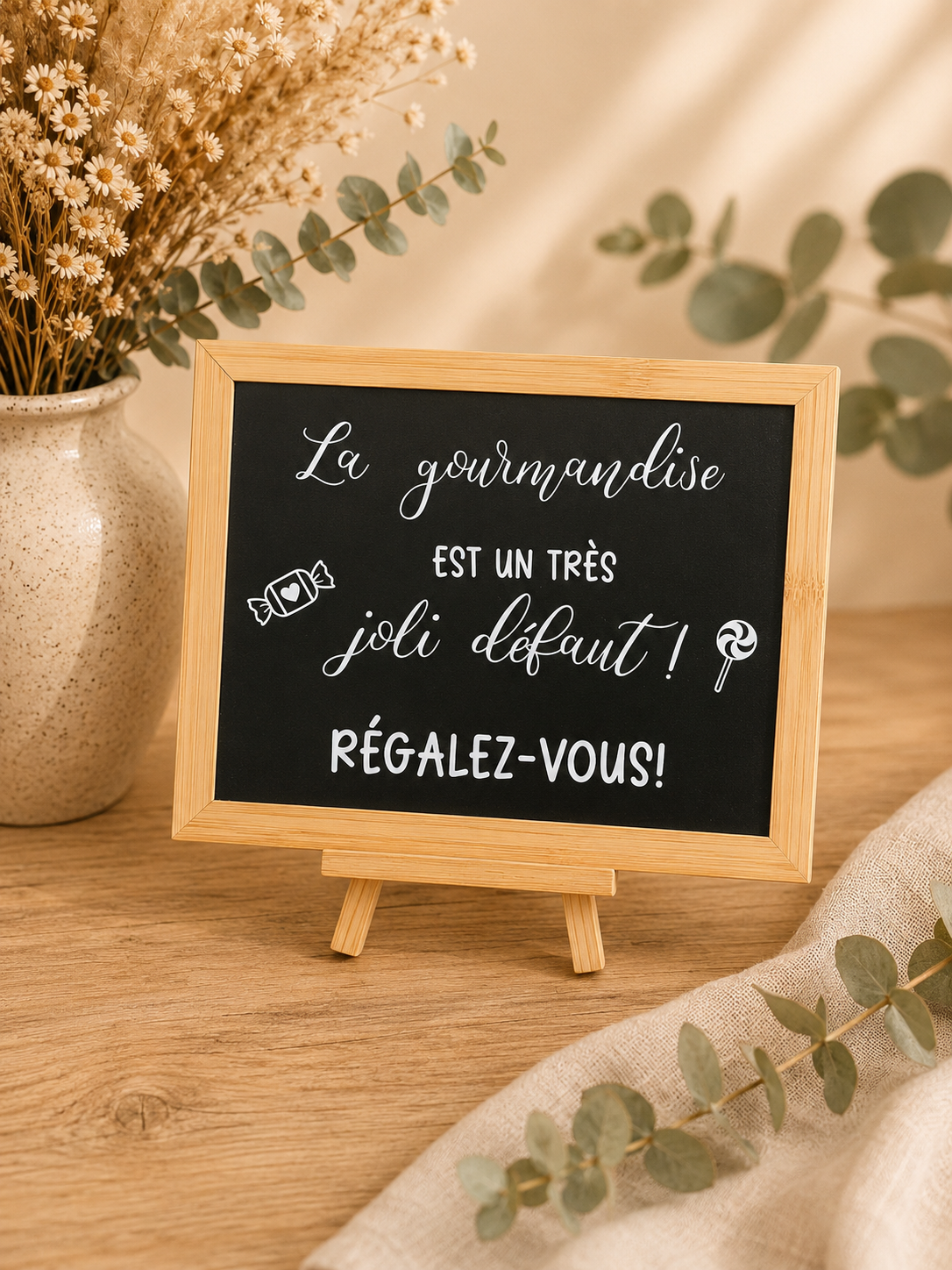 Tableau noir avec texte en français, décor de fleurs séchées dans un vase et branches de eucalyptus