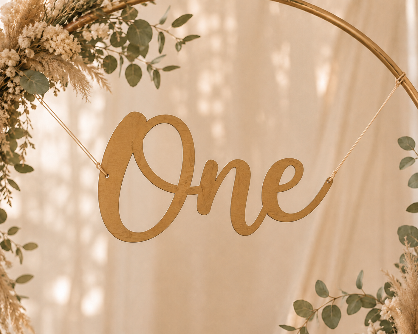 Décoration avec le mot 'One' en bois suspendu, entouré de feuillage et de fleurs.
