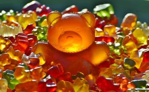 Gummy bear candies in various colors surrounding a central orange gummy bear