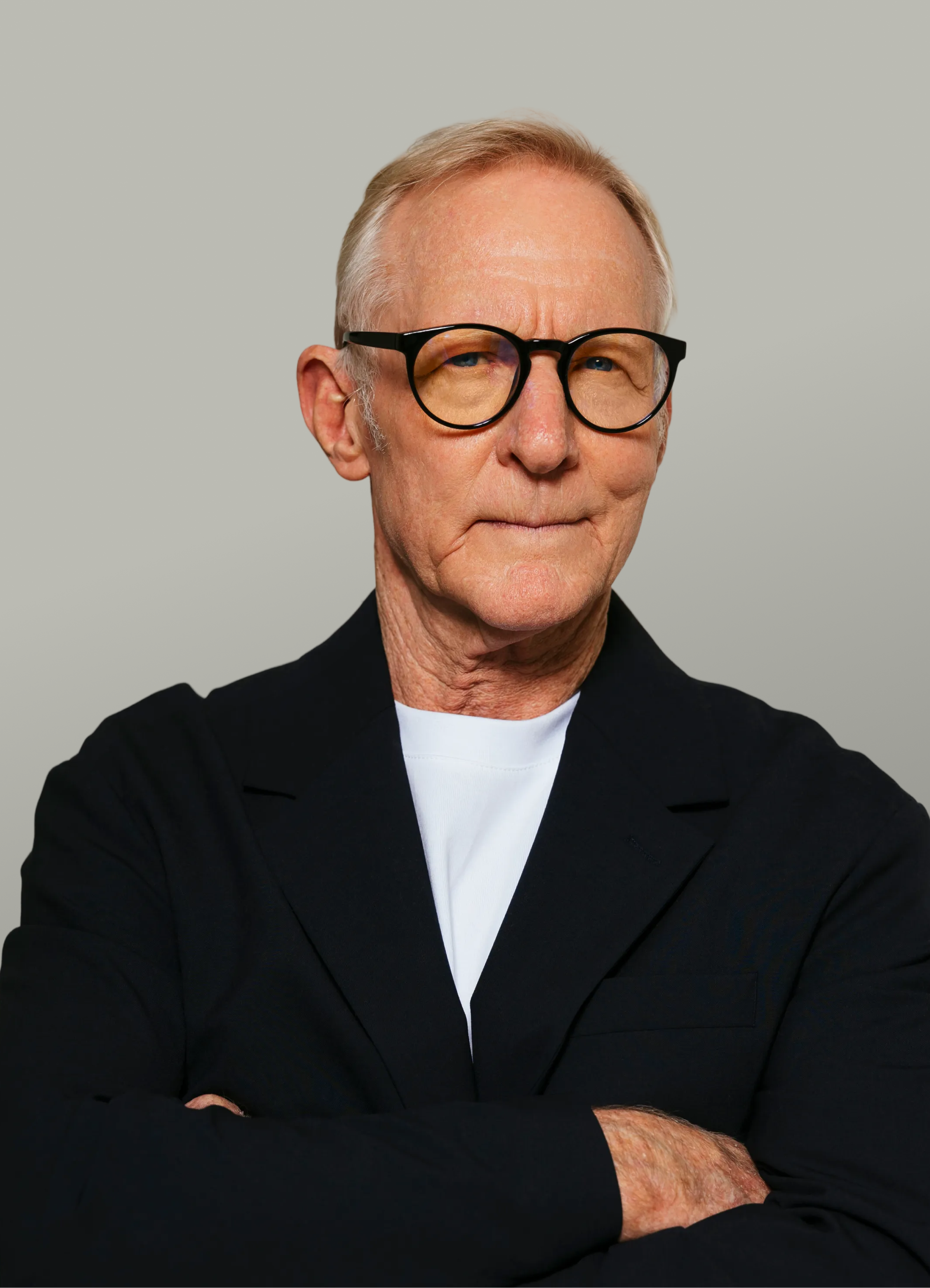 Portrait of the founder, an older man in dark blazer with rounded glasses