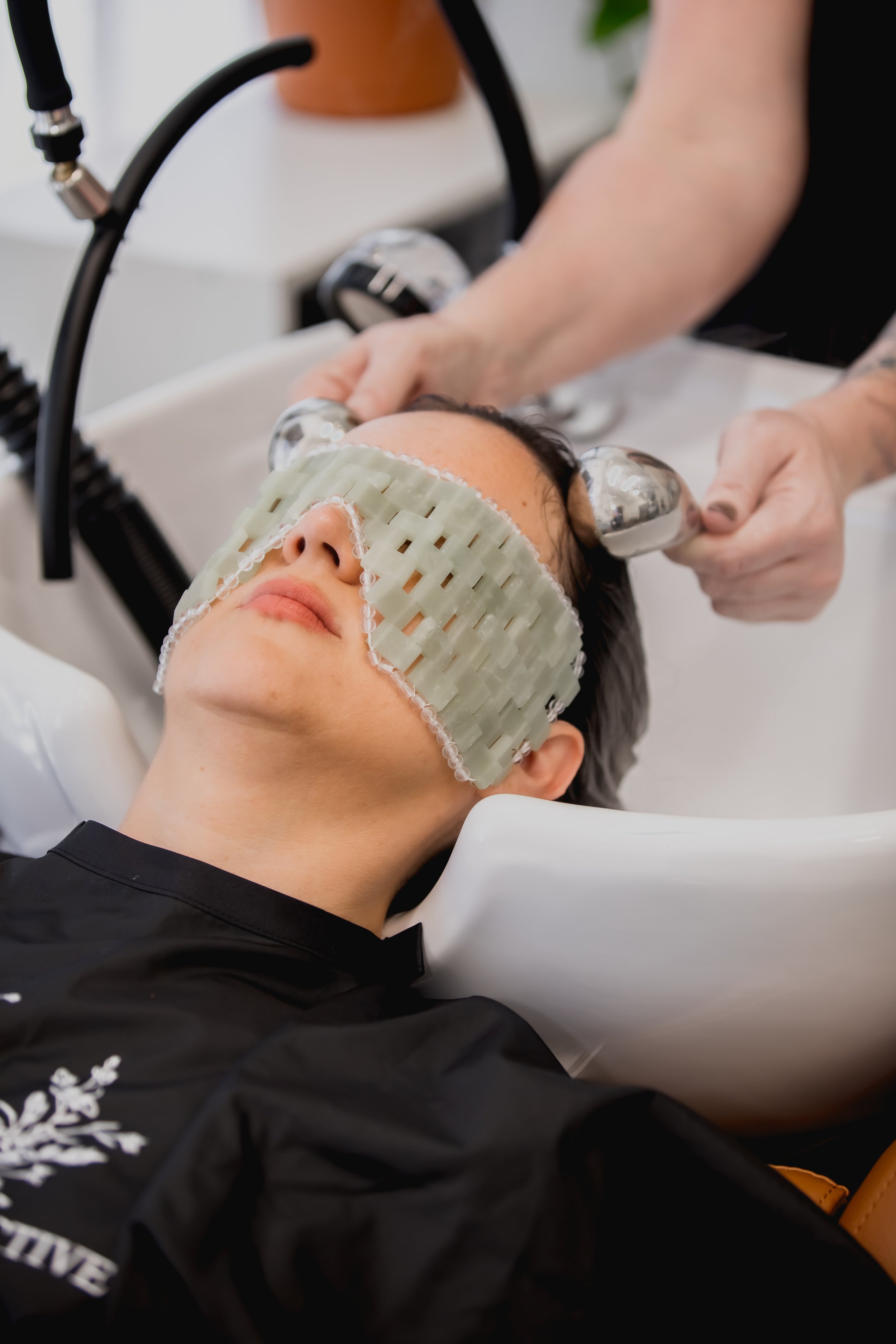 Relaxing jade stone eye mask on a customer while she receives a head spa treatment in north phoenix by Sara of Connors Collective Hair Studio who is giving a ice globe treatment while ozone steam is used.