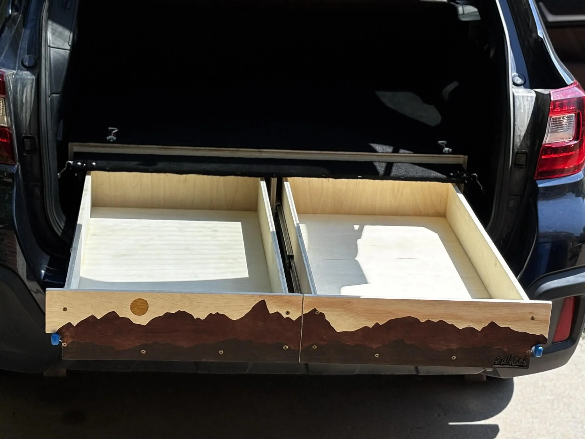 Open black SUV trunk with custom wooden drawers ready for storage or travel.