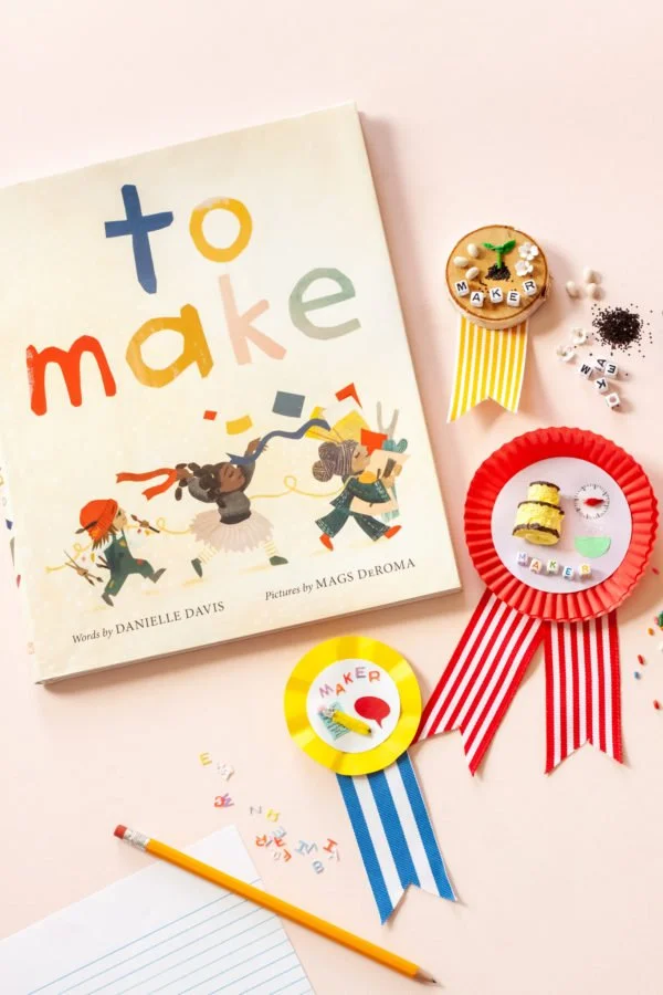 Children's book titled 'to make' with colorful letters and illustrations of children holding balloons, surrounded by handmade crafts, ribbons, and a pencil on pink background.
