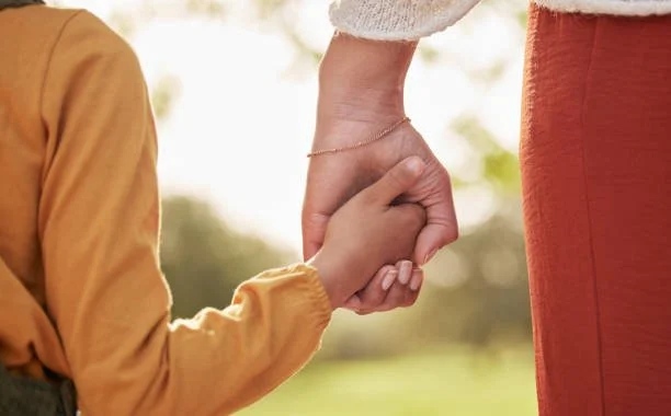 A parent and child holding hands outdoors