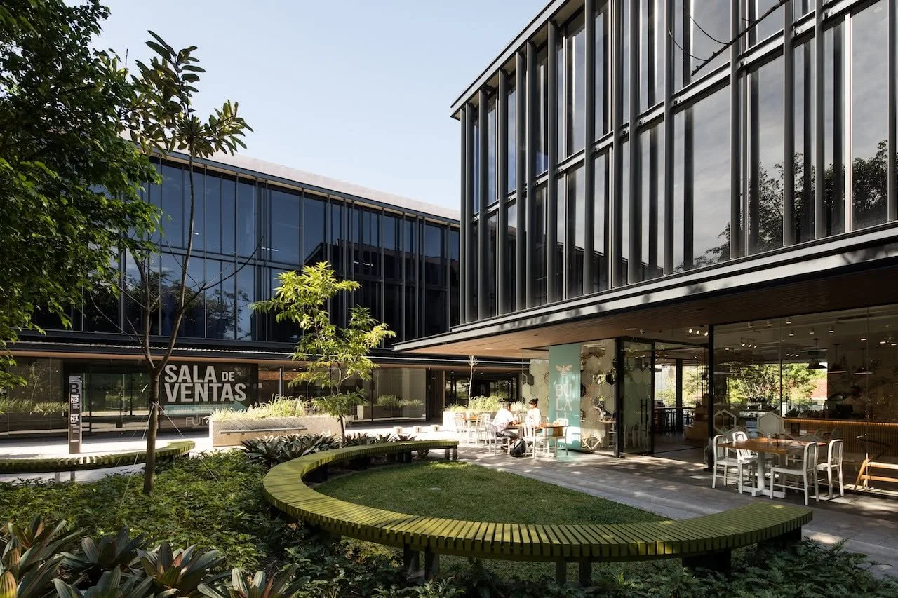 Plaza Futura, Pasaje moderno de un centro comercial con techos de madera, fachada de vidrio, restaurante al aire libre y áreas verdes.Plaza comercial moderna con edificios de vidrio, cafetería, áreas verdes y letrero de sala de ventas.
