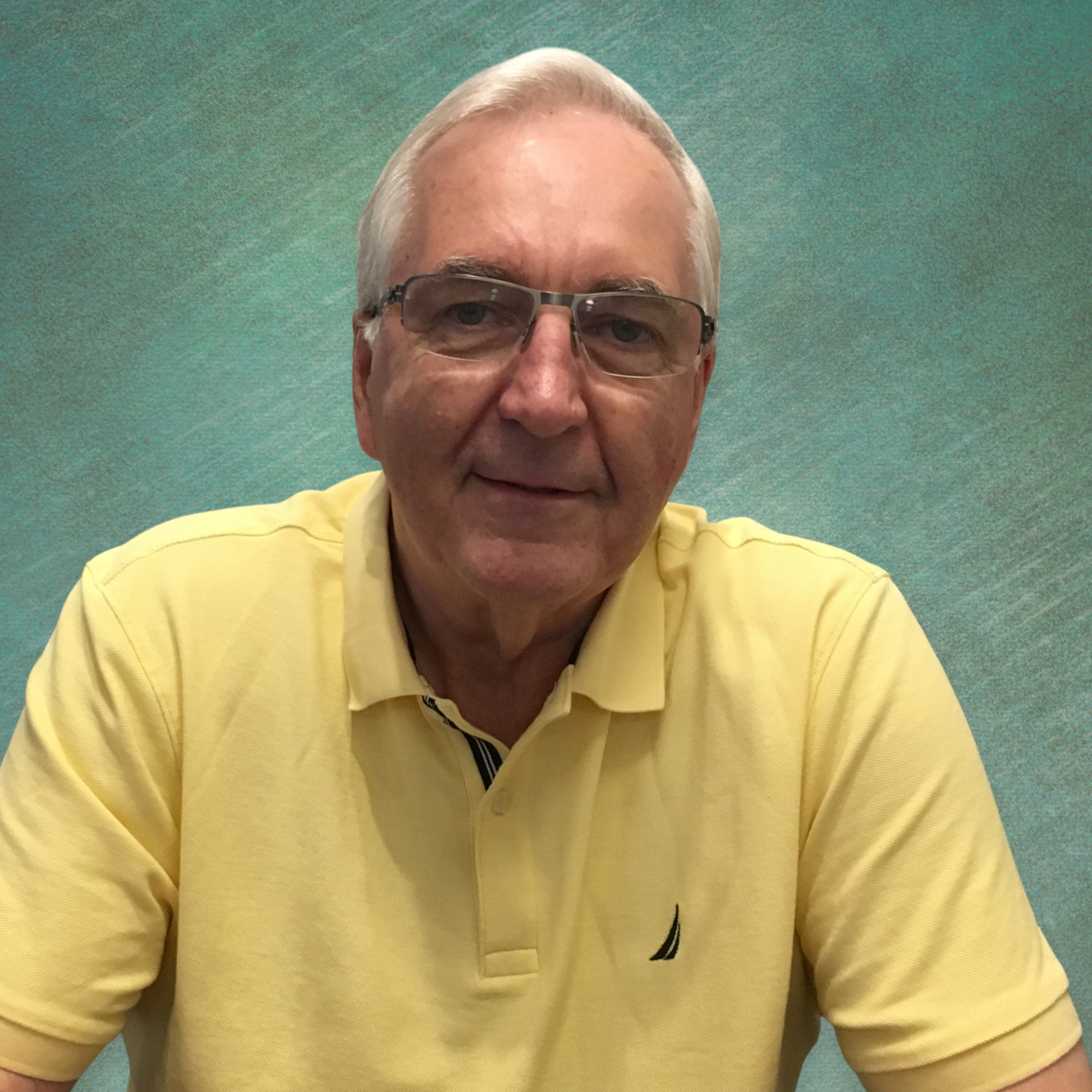 Headshot of gray haired white man in yellow shirt with glasses