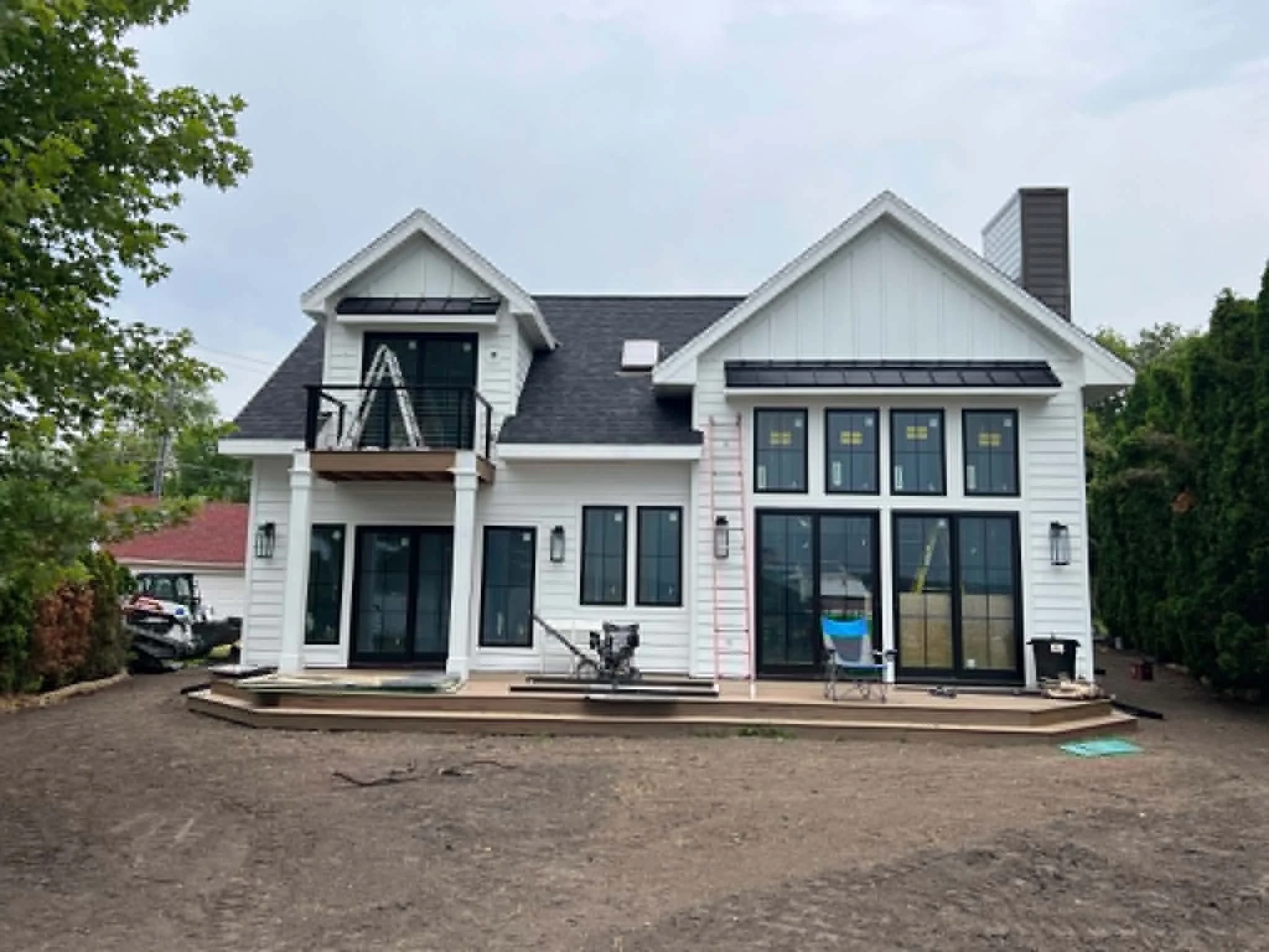 A house under construction with a white exterior, black roof, and multiple windows.