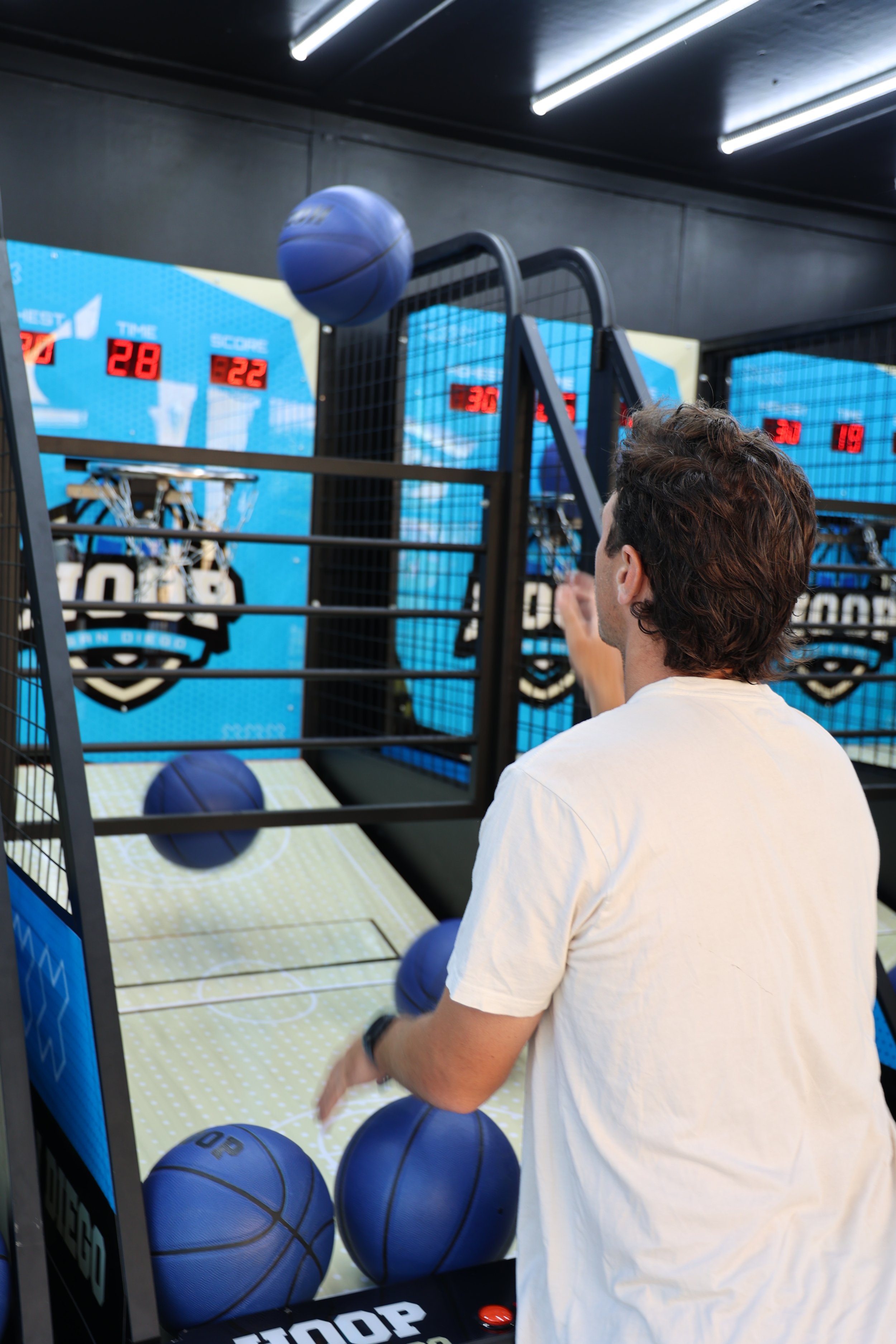 Person playing an arcade basketball game, aiming to make a shot with basketballs.
