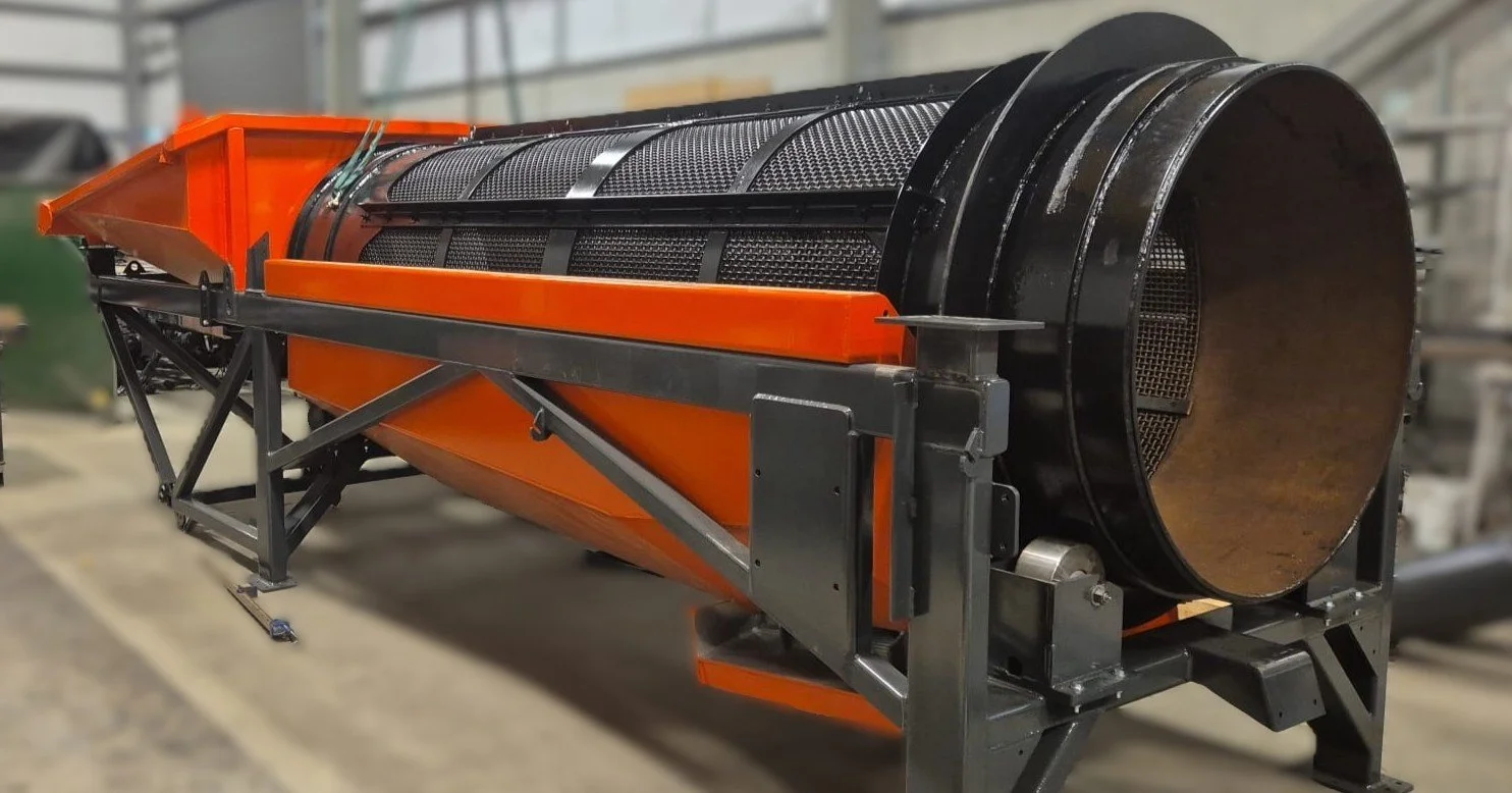 side view of gold mining trommel drum, orange painted hopper and drum supports.